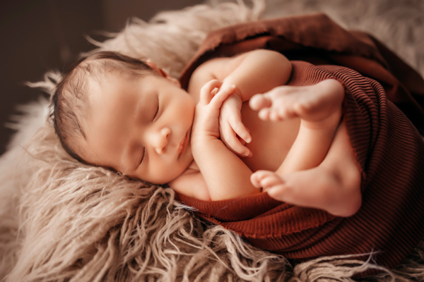 Newborn Photography, newborn swaddled in a red blanket with hands and feet showing