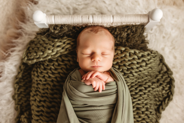 Newborn Photography, newborn baby swaddled in a green blanket with hands peeking out