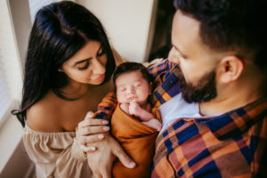 Family Photographer, a young mother and father hold their new baby