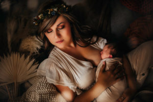 Newborn Photographer, a mother holds a nursing child in her arms